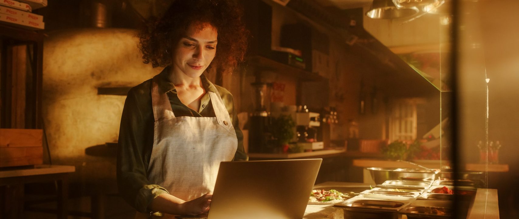 In Restaurant: Beautiful Female Chef Using Laptop Computer. Authentic Italian Pizzeria With Delicious Organic Eco Food. Bi-racial Female Entrepreneur Working in Her Small Business Family Shop